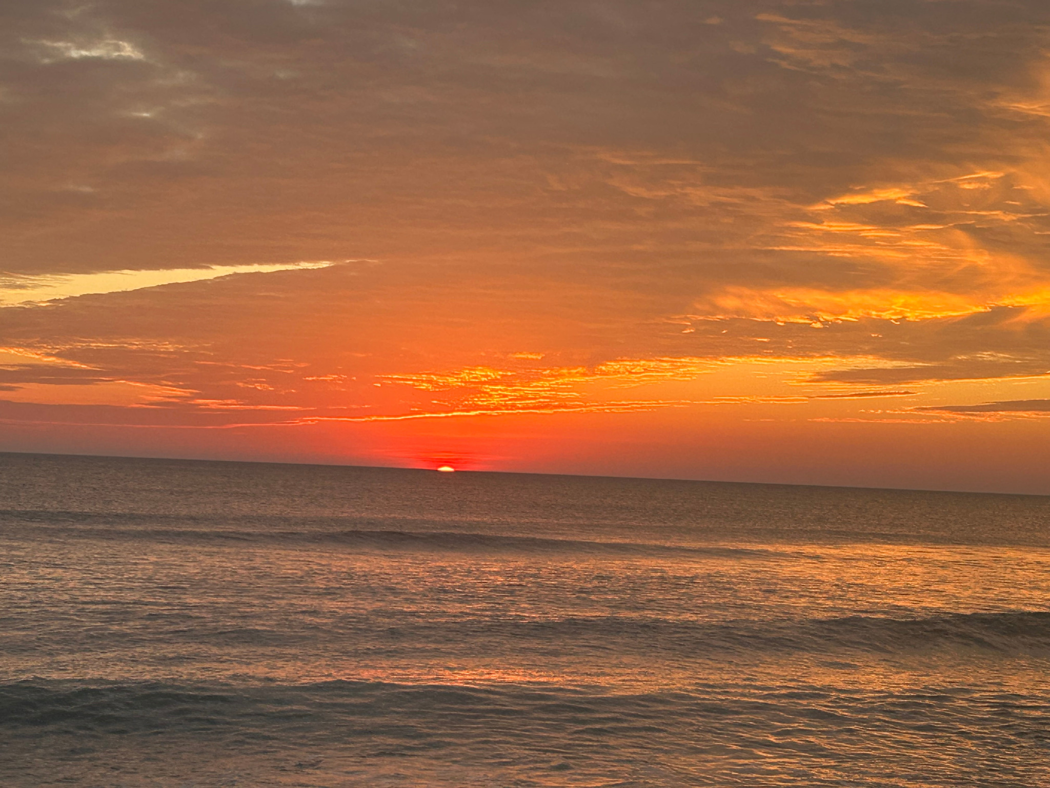 Golden sunrise over the Atlantic Ocean, with gentle waves along the beach