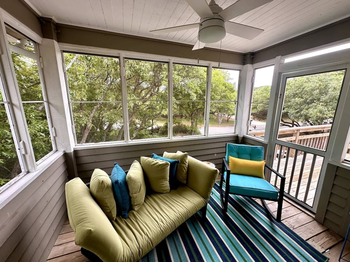 Beach Therapy screened porch with comfortable seating and leafy views