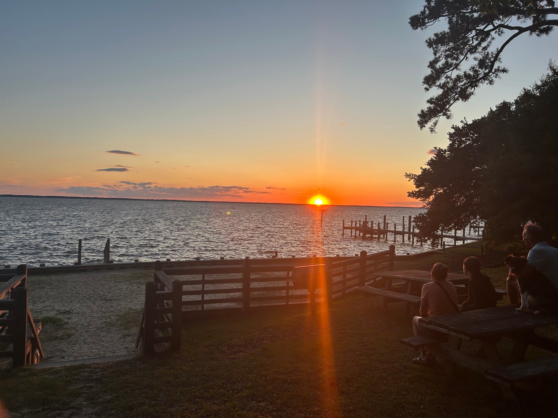 Golden sunset across the sound, with people enjoying picnic tables beside the waterfront
